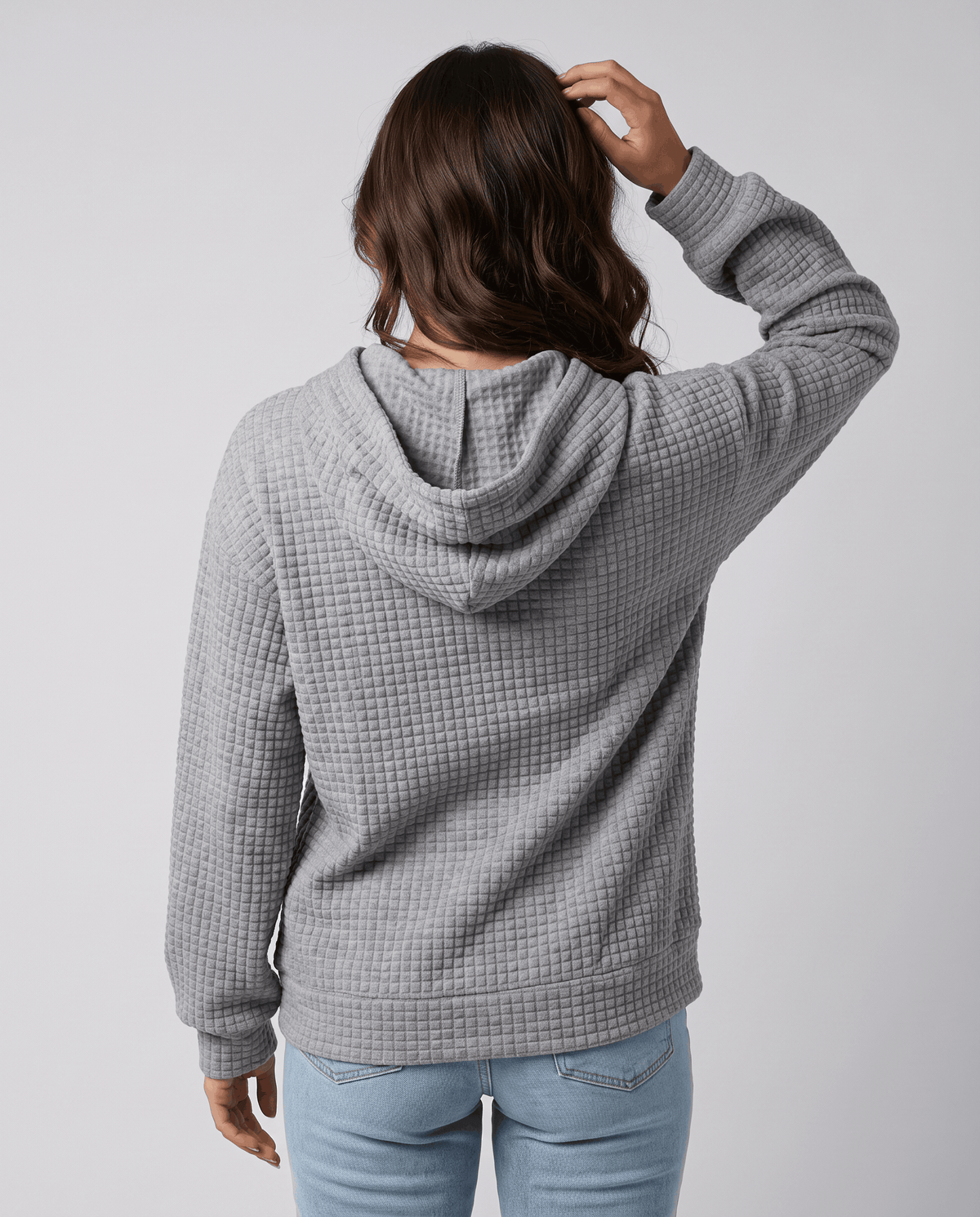 Back of gray pullover hoodie with a hand on the hood and relaxed fit