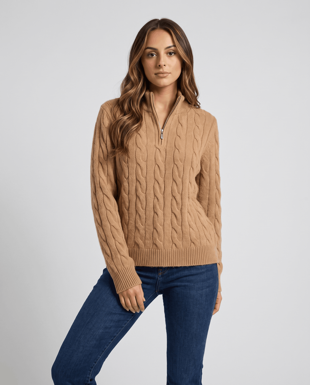 Woman in camel cable-knit half-zip sweater with blue jeans