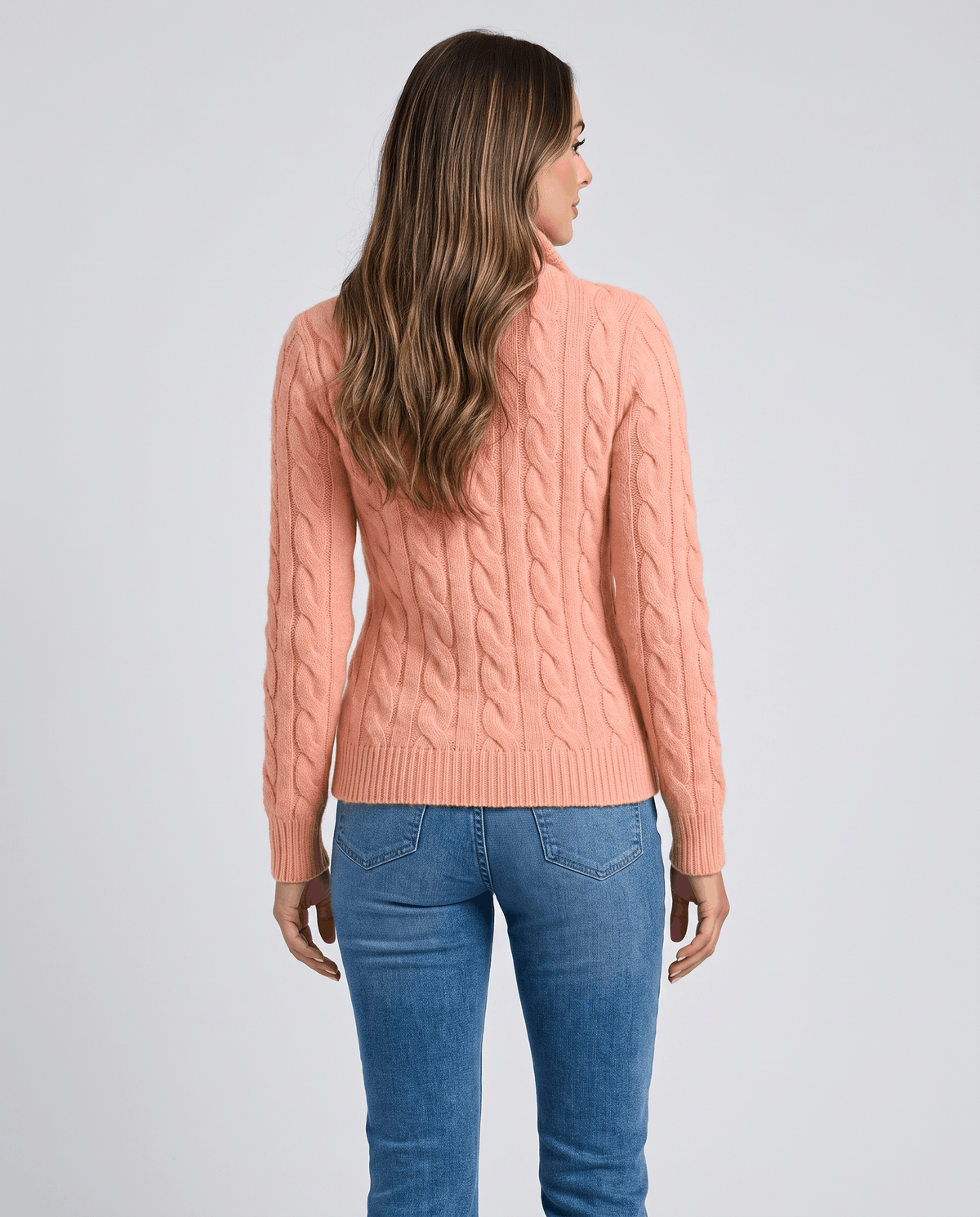 Back view of coral cable-knit sweater with light blue jeans