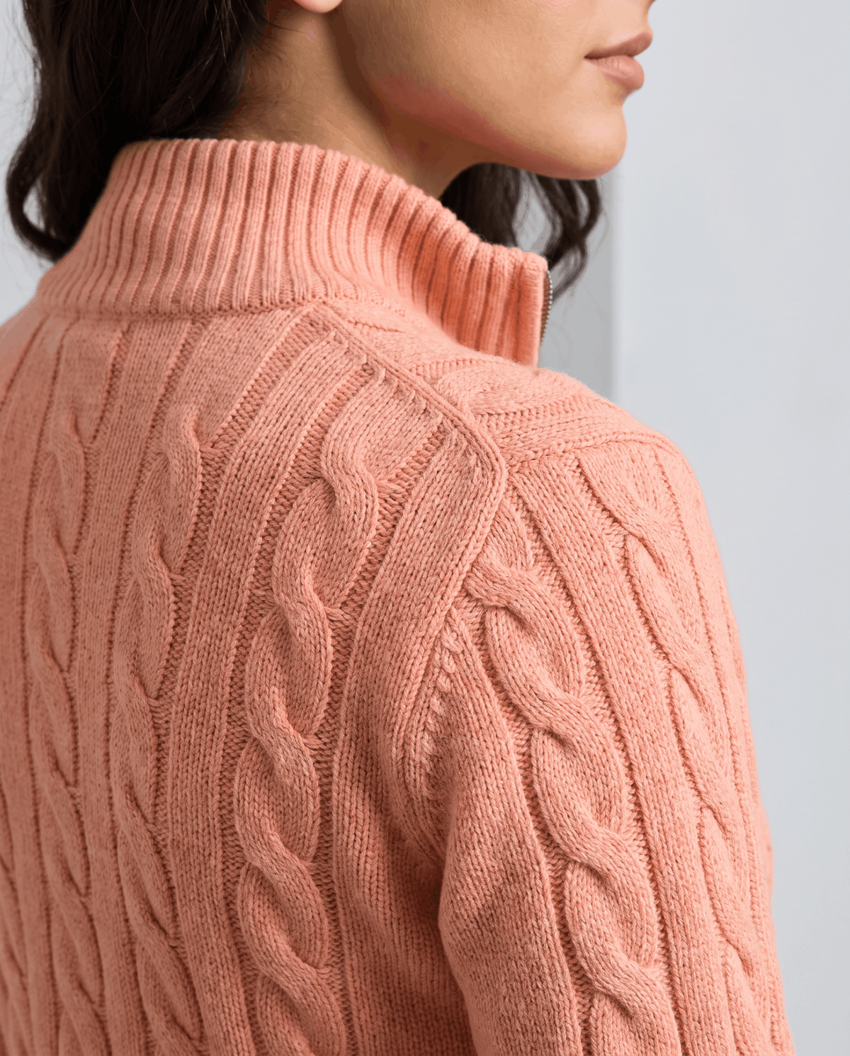 Rear detail of the coral sweater's stand collar and cable-knit shoulder