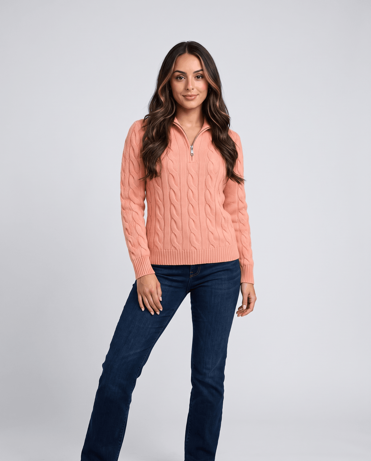 Woman in coral wool-blend cable-knit half-zip sweater with blue jeans