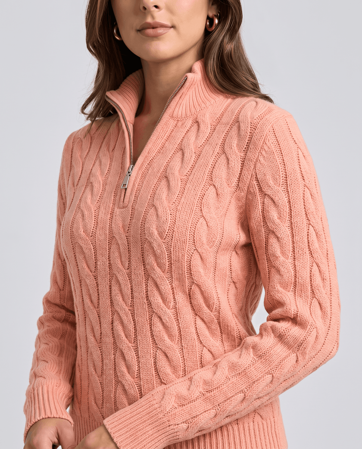 Close-up of the silver-tone half zip and cable knit on a coral sweater