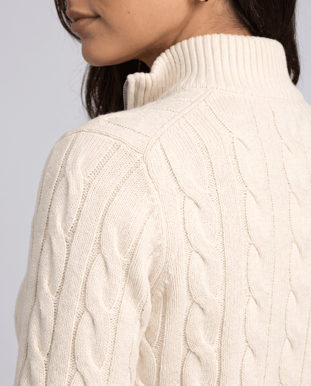 Rear detail of the cream sweater's stand collar and cable pattern