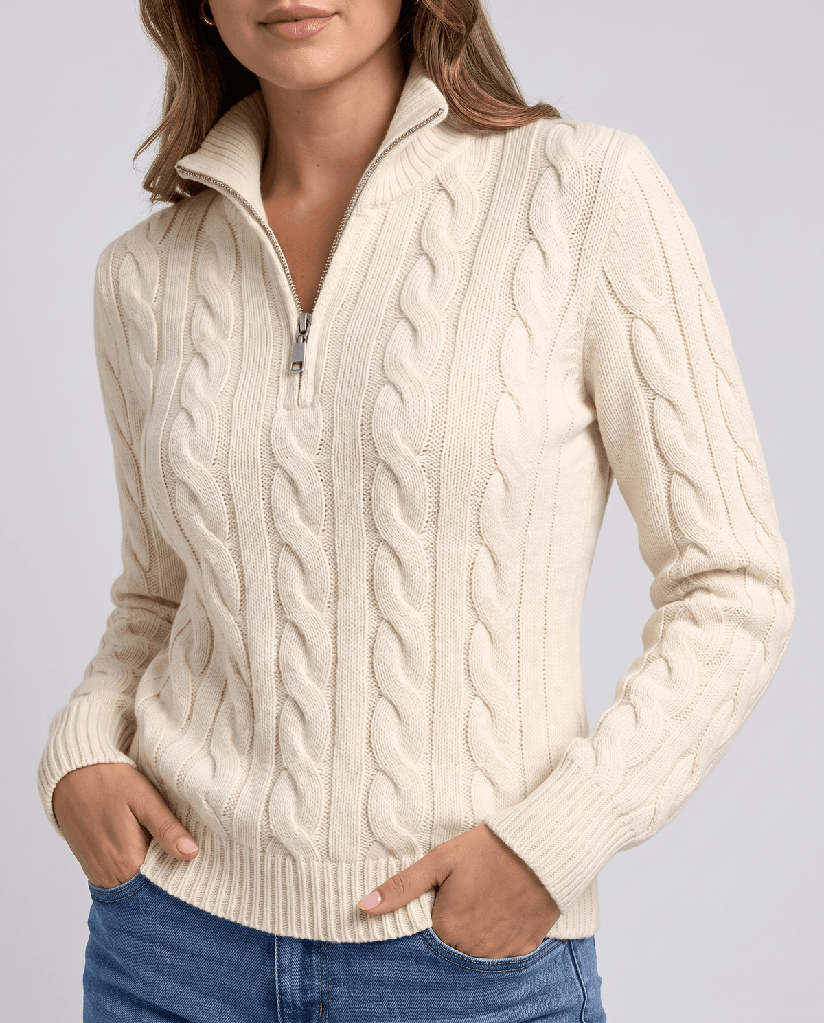 Cream cable-knit sweater worn with hands in jean pockets