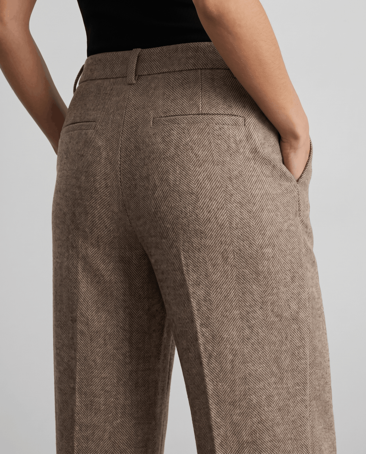 Back detail of camel trousers showing welt pocket and hand in side pocket