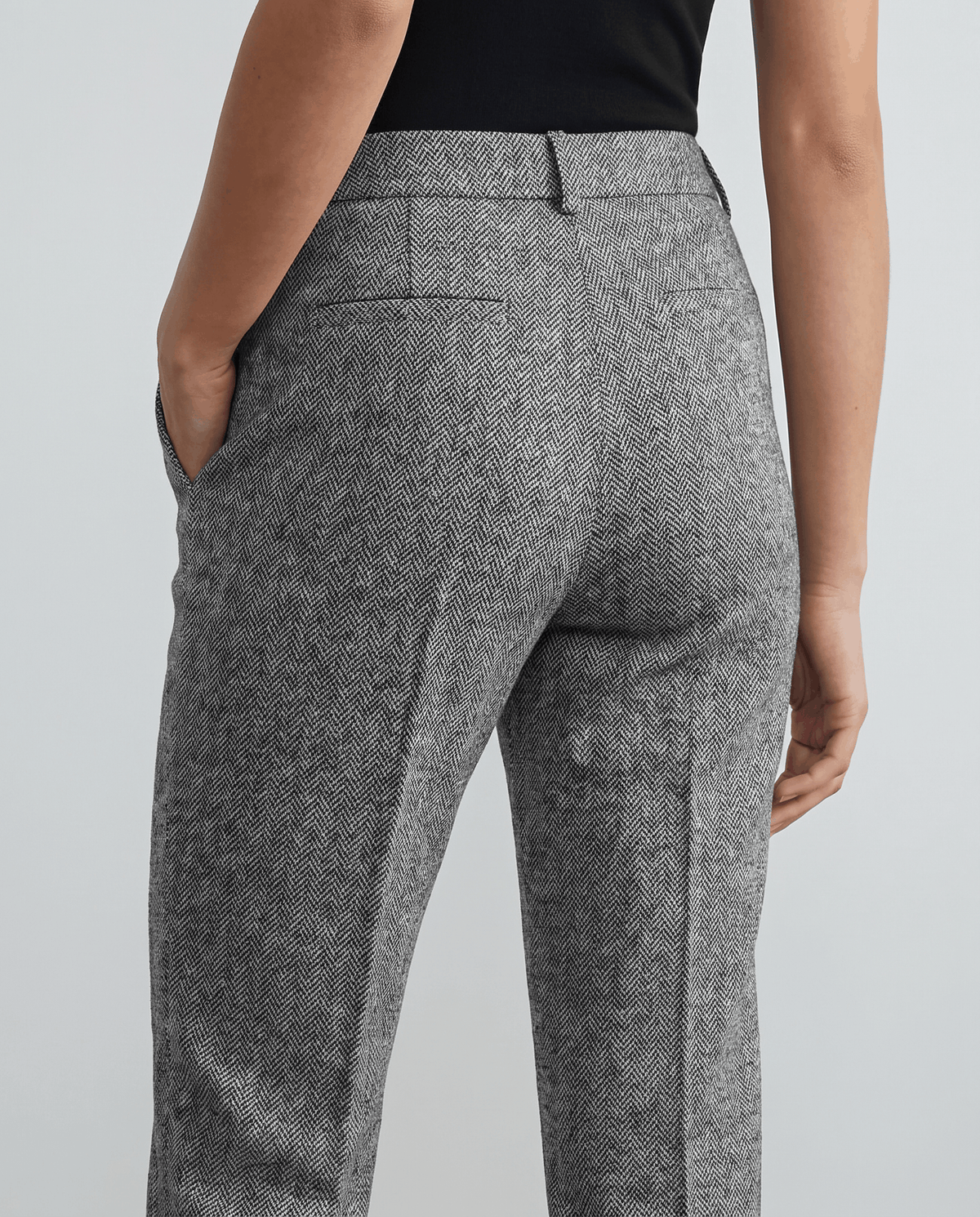 Back detail of gray tweed trousers with welt pocket and hand in pocket
