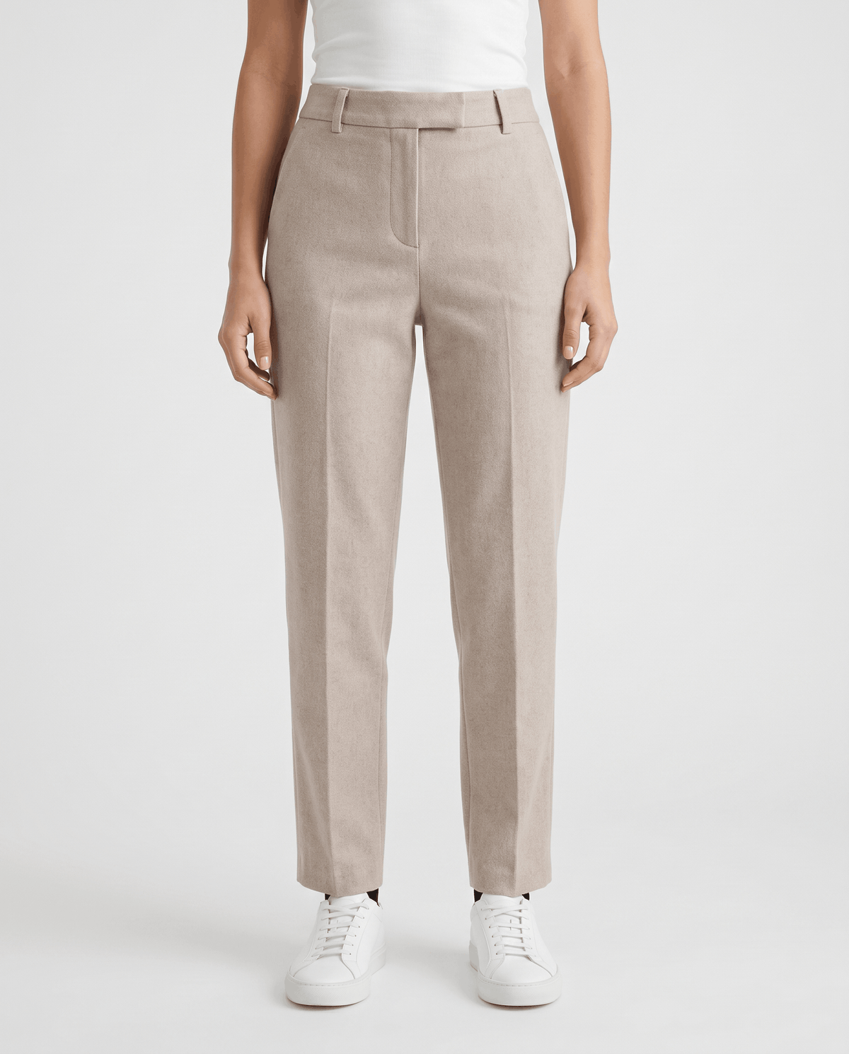 Light ivory tailored trousers in front view with pressed crease and sneakers