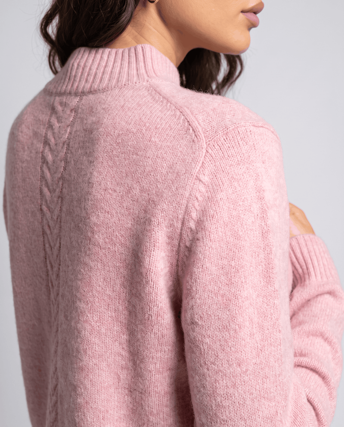Close-up of the cable detail and ribbed mock neck on the back of the pink pullover