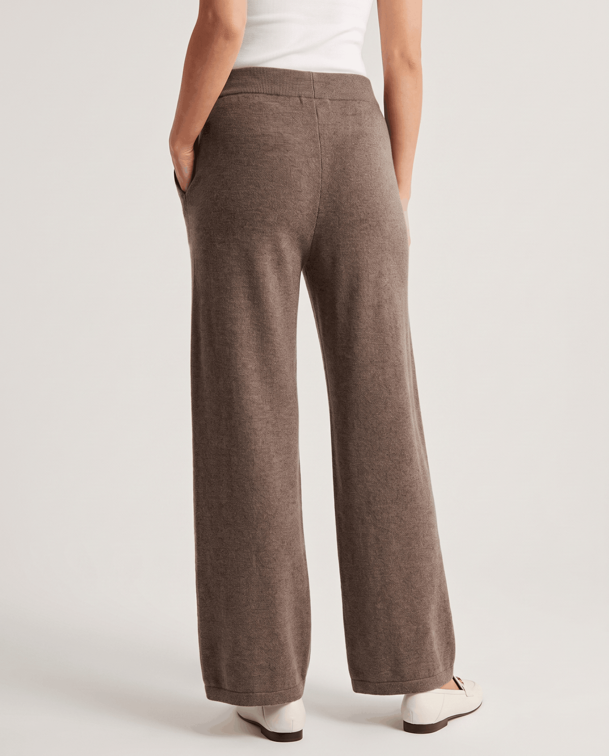 Back view of beige full-length wide-leg pants with white flats