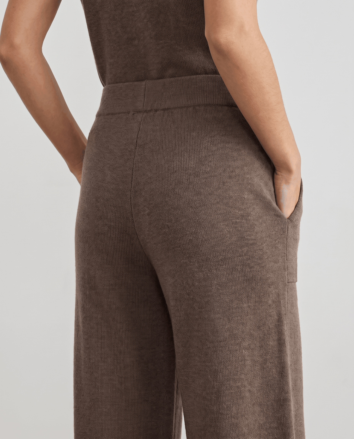 Back close-up of beige knit pants with hand in pocket