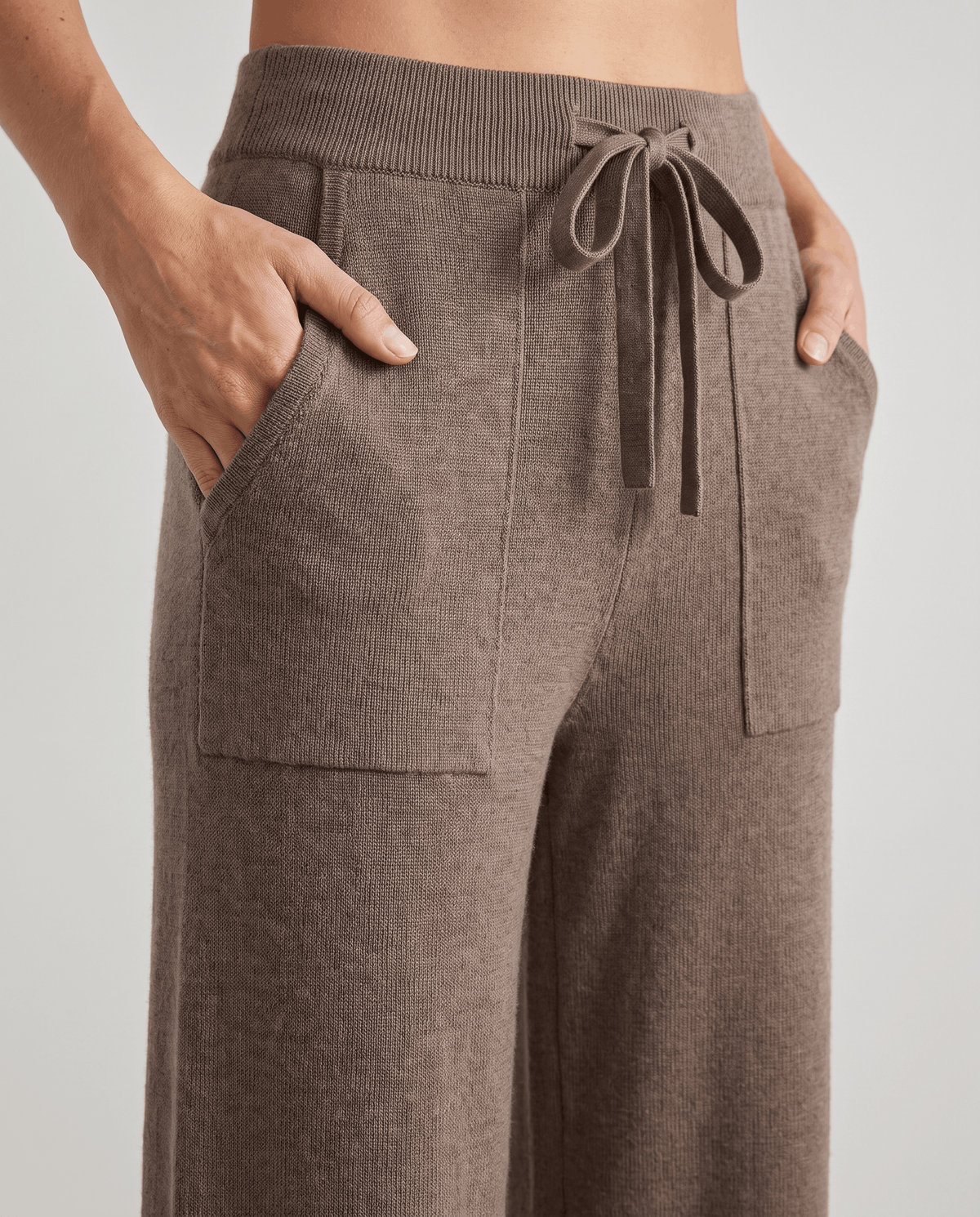 Front close-up of beige drawstring tie and two patch pockets