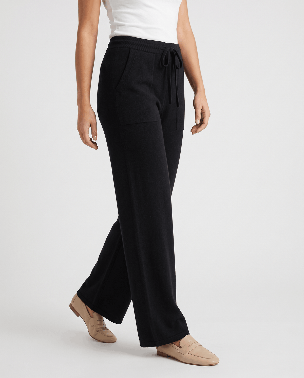 Black knit pants in three-quarter side view with drawstring and loafers