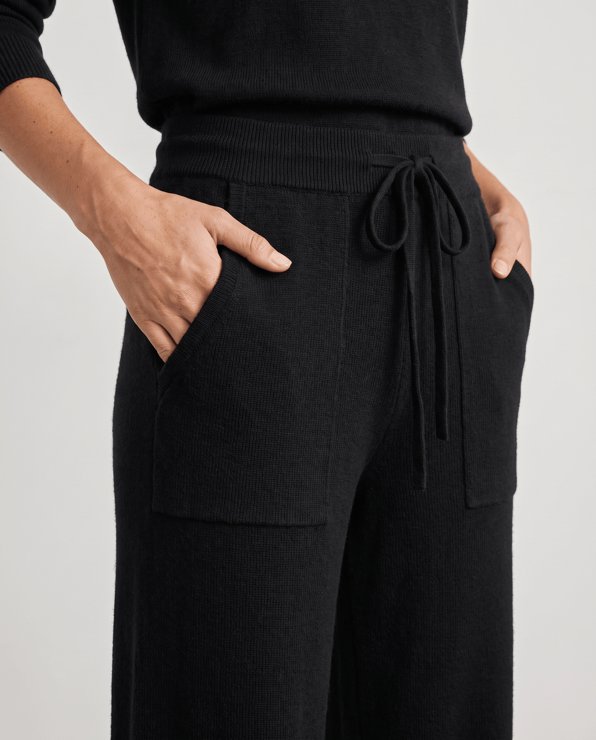 Close-up of black drawstring waist with hands in front patch pockets