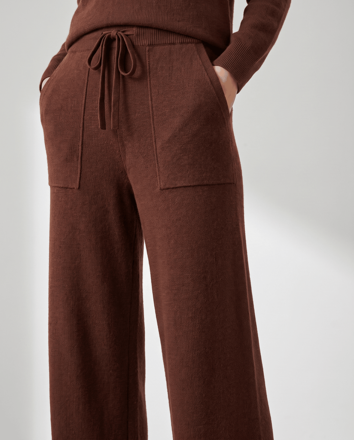 Close-up of brown drawstring waist and front patch pockets with hand in pocket