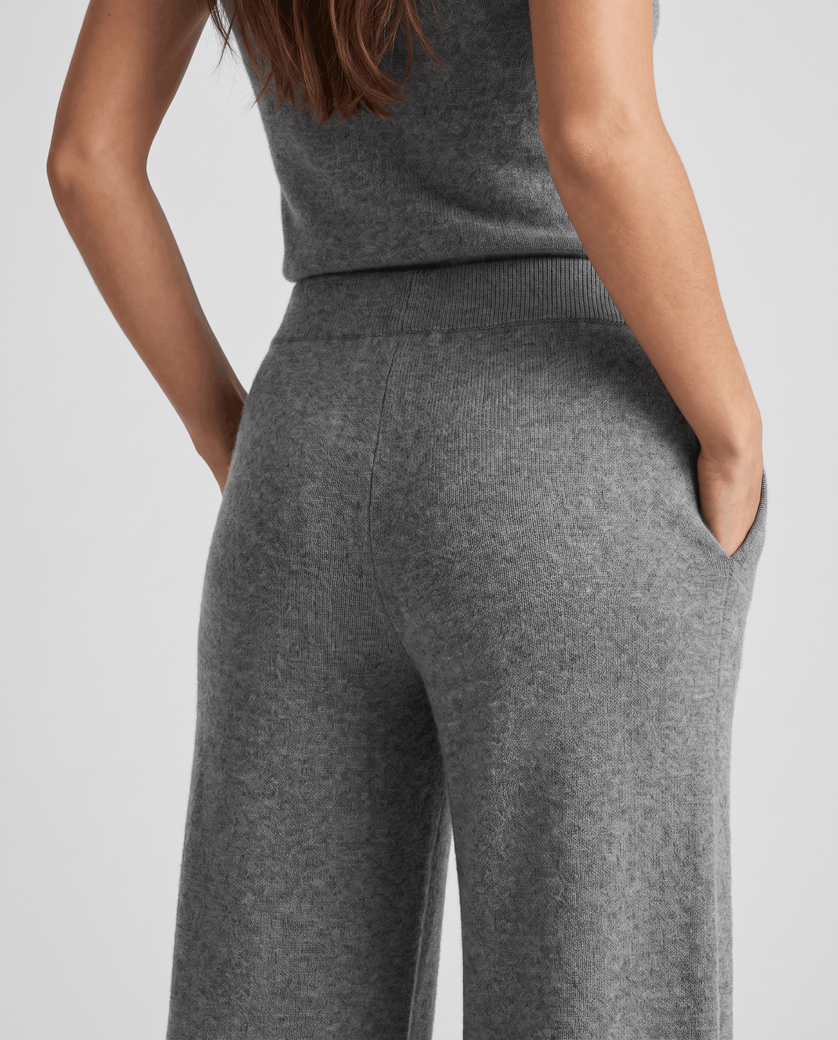 Back detail of gray knit pants with matching top and hand in pocket