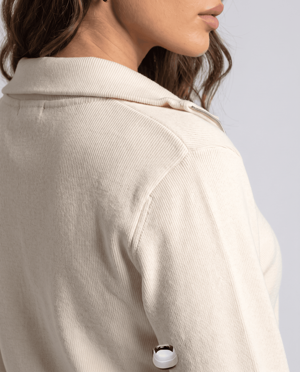 Close-up of the collar and shoulder seam on the beige knit cardigan